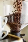 Кавові зерна потрапляють у кавоварку — стокове фото