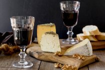 Prato de queijo com pão, nozes e vinho tinto em copos — Fotografia de Stock