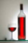 Glass and bottle of red wine (out of focus) — Stock Photo
