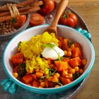 Curry de batata con garbanzos, canela, tomate, espinacas, garam masala, cilantro, arroz y yogur natural - foto de stock