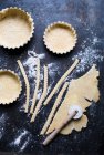 Pie pastry in cases, rolled out on a floured surface, and cut into strips - foto de stock