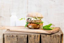 Um hambúrguer com salada de repolho numa tábua de madeira — Fotografia de Stock