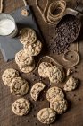 Biscoitos de chocolate com copo de leite e pedaços de chocolate derramados — Fotografia de Stock