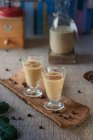 Creamy coffee liqueur in a carafe and served over ice in liqueur glasses — Foto stock