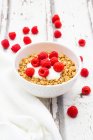 Granola with yoghurt and raspberries in bowl on rustic wooden surface — Stock Photo