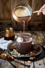 Heiße Schokolade mit Erdnusskaramell wird in eine Tasse gegossen — Stockfoto