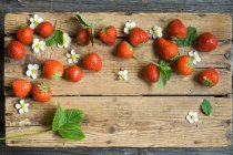 Erdbeeren mit Blättern und Blüten auf Holzbrett — Stockfoto