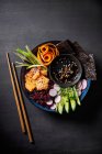 Sushi buddha bowl con arroz rojo, salmón, nori, verduras y salsa de soja - foto de stock