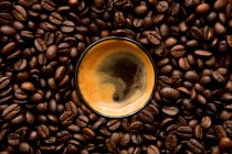 Espresso in the midst of coffee beans, supervision — Stock Photo
