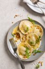 Fresh homemade pumpkin ravioli tortellini parcels on plate topped with pine nuts, parmesan and rocket — Stock Photo