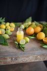 Jus d'orange fraîchement pressé et agrumes frais sur une table en bois rustique — Photo de stock