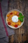 Espaguetis con pesto rosso, tomates cherry y burrata - foto de stock