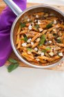 Penne in a tomato sauce with goats cheese in a saucepan — Stock Photo