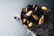 Fresh mussels in black ceramic bowl on dark concrete background — Stock Photo