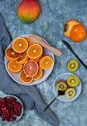 Frutta fresca: arance rosse, mango, cachi, kiwi e bacche ghiacciate — Foto stock