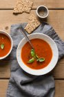 Tomato soup with fresh basil on a wooden table — Stock Photo