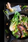 Жареная утиная грудь с лапшой, овощами, кинзой и арахисом в чугунной сковороде — стоковое фото