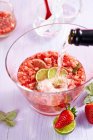 Champagne being added to strawberry punch — Stock Photo
