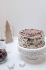 Ein Schokoladenkuchen auf einem Kuchenstand auf einem weihnachtlich dekorierten Tisch — Stockfoto