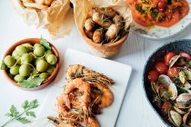 Prawns with chilli and garlic, clams with tomatoes, onion rings and olives - foto de stock