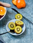 Kiwi halves with spoons in ceramic bowls — Stock Photo