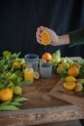 Sumo de laranja fresco e citrinos frescos em uma mesa de madeira rústica — Fotografia de Stock