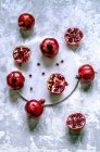Fresh pomegranates whole and cut with scattered grains on a marble tray — Stock Photo