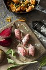 Gnocchi di barbabietola su un tagliere con salvia fresca, barbabietola cruda, parmigiano e piatto cotto — Foto stock