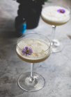 Whiskey Sour cocktails served with purple flowers in glasses — Stock Photo