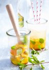 Orange and lime punch with cachaca and mint in jars — Stock Photo