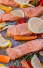 Lemon salmon with peppers, carrots, olive oil and rosemary on baking paper — Stock Photo