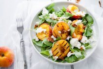 Свежий салат с персиковыми половинками, рукколой и бурратой — стоковое фото
