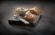 Chive cream cheese cream in a bowl and on baguette slices — Stock Photo