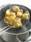 Tortellini frais dans un tamis avec une casserole d'eau bouillante — Photo de stock