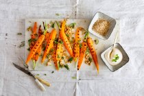 Cenouras grelhadas com farro, cebolinha, folhas de cenoura, sementes de gergelim e molho de iogurte — Fotografia de Stock