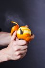 Руки очищая оранжевый с ножом, видимый сок распыления — стоковое фото
