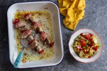 Espetos com frango em bacon, cogumelos e pimenta vermelha, salada de alface, tomate, pimentão, pepino — Fotografia de Stock