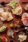 Bruschetta con pesto, mini salami, aceitunas, parmesano, aceite de oliva, alcaparras gigantes y vino tinto - foto de stock