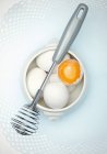 Eggs and a whisk — Stock Photo