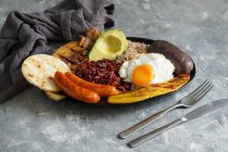 Bandeja paisa - Колумбийский жареная свинина живот, черный пудинг, колбаса, арепа, бобы, жареный банан, яйцо авокадо, и рис — стоковое фото