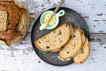 Sourdough bread sliced on a metal tray with butter on the side — Stock Photo