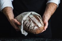 Человек, держащий в руках хлеб из цельной пшеницы, приготовленный с ароническим (черничным) порошком — стоковое фото