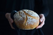 Primer plano de deliciosa barra de pan en tus manos - foto de stock