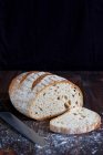 Pane di grano e fetta su superficie di legno con coltello e farina — Foto stock
