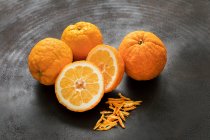 Fresh bitter oranges with zest on black metal — Stock Photo