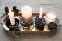 Vier brennende Kerzen mit Weihnachtsschmuck auf Tablett — Stockfoto