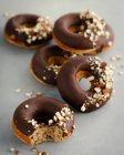 Donuts de avelã com esmalte de chocolate e avelãs picadas — Fotografia de Stock