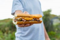 Чоловік тримає бутерброд зі стейком — стокове фото