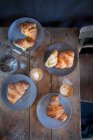 Croissants with cappuccinos on a rustic wooden table (top view) — Stock Photo
