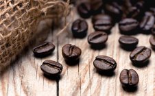 Смажені кавові зерна на дерев'яній поверхні (зблизька).) — стокове фото
